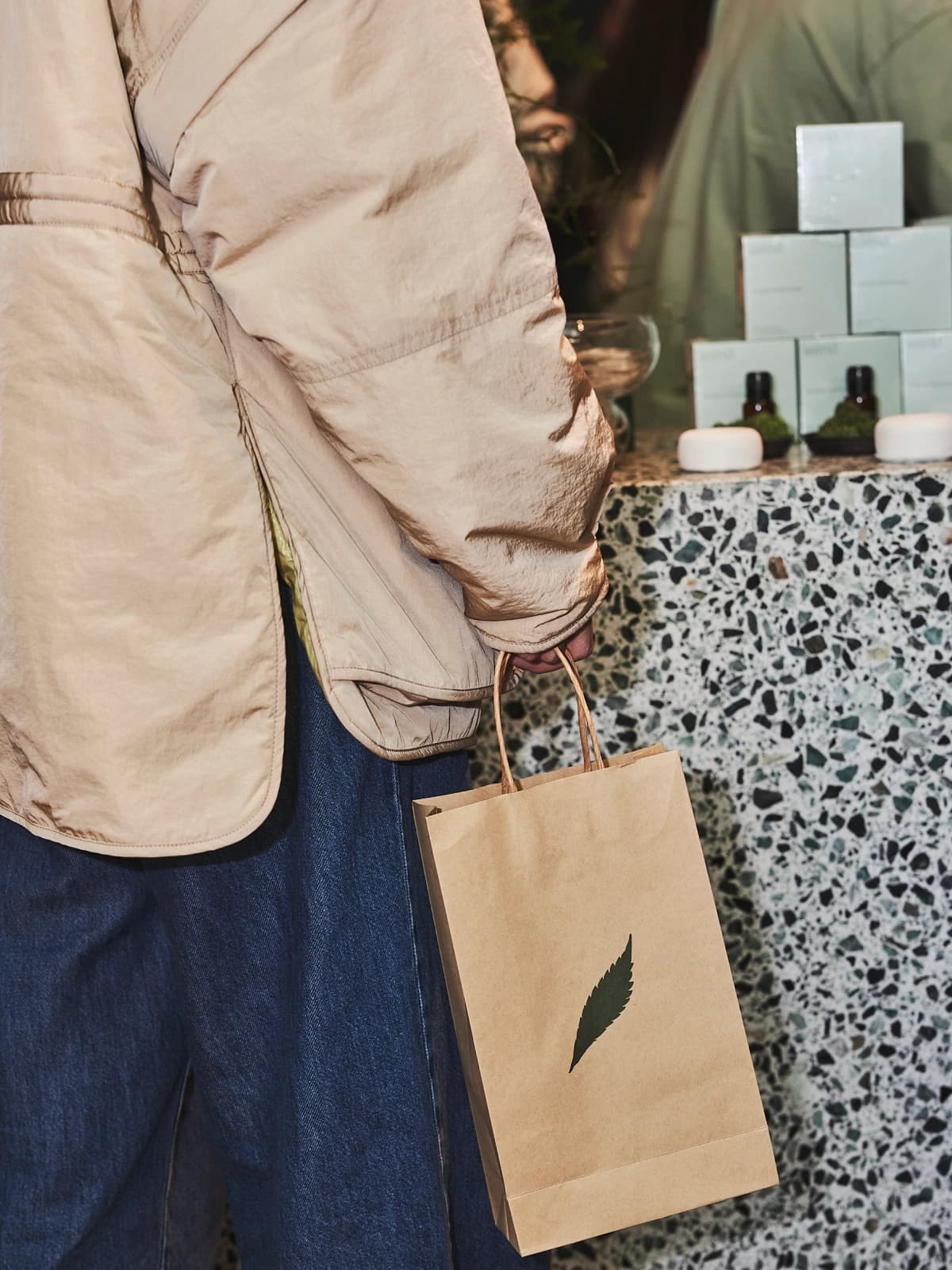 A customer holding and astrid bag with a small green leaf printed on it